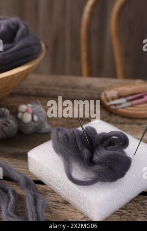 Felting tools, wool and toy cat on wooden table Stock Photo
