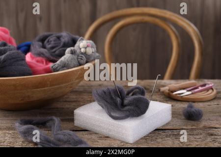 Felting tools, wool and toy cat on wooden table Stock Photo