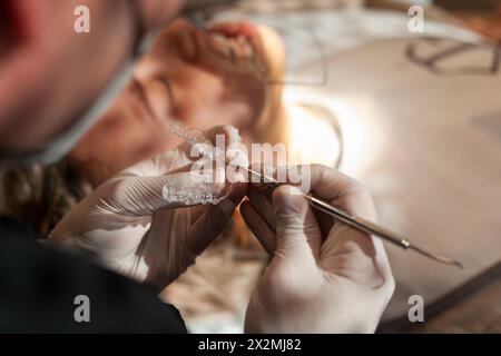 Close-up of an orthodontic specialist holding an invisible aligner in his hand. Concept of invisible orthodontic technique. Stock Photo