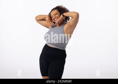 Biracial plus size young female model poses, hands on head, smiling, white background, copy space Stock Photo