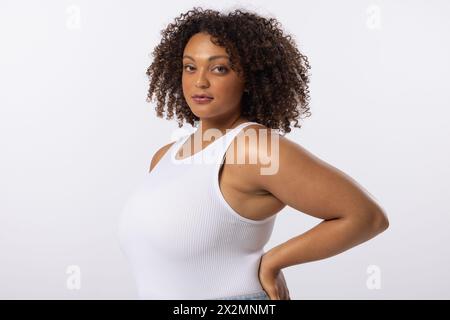 A biracial young female plus size model poses on white background, copy space Stock Photo