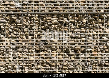 Texture of pebbles in metal grille cages stacked upon each other, used as bricks and protection. Stock Photo