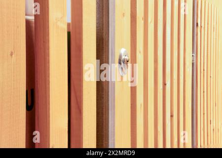 Basement storage compartment with wood lattice door and lock. Metal protection at the wooden slat where the lock is mounted. Stock Photo
