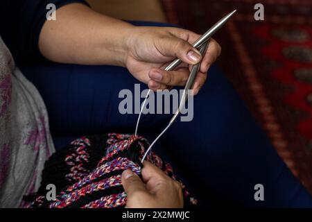 Close-up of Latin American woman's hands holding a type of circular needles ideal for knitting long lengths in the round with wool material yarns, Con Stock Photo