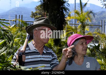 Two Latin American seniors walk through their backyard garden, Retired and Leisure Concept Stock Photo