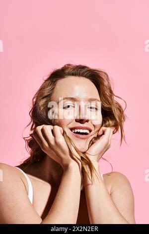 A radiant woman smiles joyfully, hands delicately framing her face in a moment of pure beauty and happiness. Stock Photo