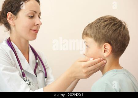 Doctor checks little boy lymph nodes, focus on boy Stock Photo
