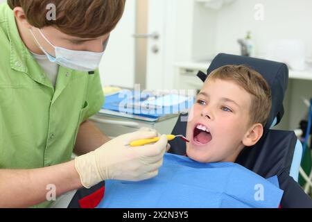 Young dentist looks at teeth of little boy in dental clinic. Focus on patient. Stock Photo