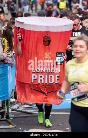 Scott Lofthouse participating in the TCS London Marathon 2024 passing through Tower Hill, London, UK, wearing Fullers London Pride pint glass costume Stock Photo