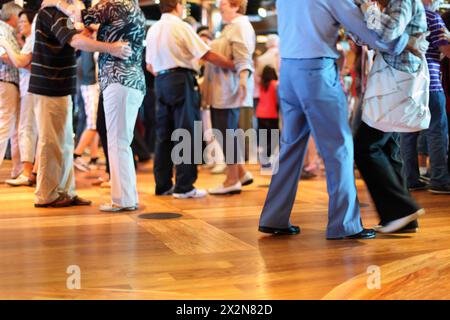 Many happy senior couples in love dancing on wooden dance floor. Focus on right shoe. Stock Photo