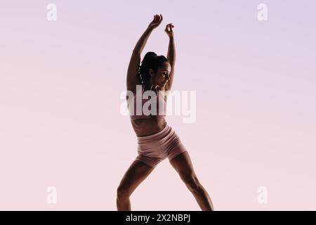 Female dancer in fitness clothing gracefully performs a classical ballet routine. With precise technique and flexibility, she showcases her profession Stock Photo