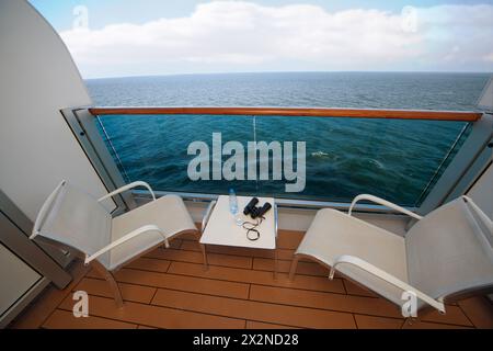 balcony with chairs table bottle glass with water binoculars on ship with view on sea Stock Photo