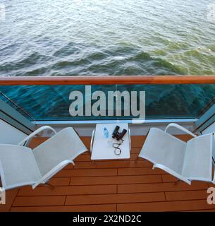 balcony with chairs table bottle glass binoculars on ship , view from above Stock Photo