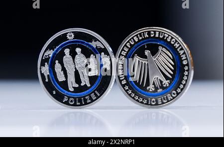 Hamburg, Germany. 23rd Apr, 2024. Two new 10-euro 'Police' commemorative coins stand on a tray in the Hamburg Mint and are illuminated from behind. The collector's coin is part of the multi-year series 'In the service of society' and depicts several police officers on duty. Credit: Christian Charisius/dpa/Alamy Live News Stock Photo