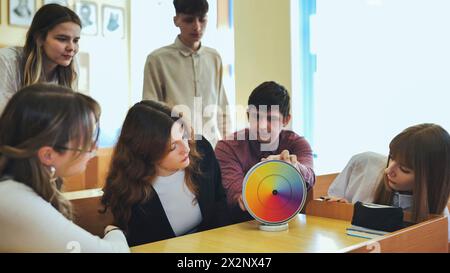 Students in physics class spin Newton's multicolored disk. Stock Photo