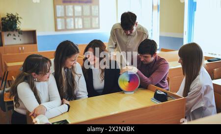 Students in physics class spin Newton's colorful wheel. Stock Photo