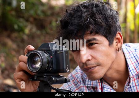 outdoor lifestyle concept. closeup of young latin photographer using retro camera Stock Photo
