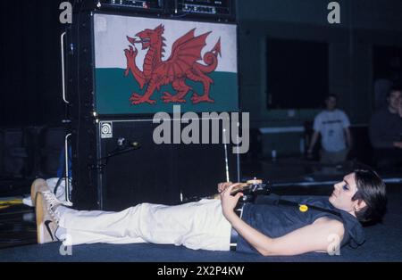 MANIC STREET PREACHERS, NICKY WIRE, CONCERT, 1998: Nicky Wire of Welsh band Manic Street Preachers lying on the stage in front of his bass amp draped in a Welsh flag playing at Afan Lido, Port Talbot, Wales, UK on 20 September 1998. The band were touring with their 5th album 'This Is My Truth Tell Me Yours'. Photo: Rob Watkins. INFO: Manic Street Preachers, a Welsh rock band formed in 1986, emerged as icons of the '90s British music scene. Known for their politically charged lyrics and anthemic melodies, hits like 'A Design for Life' solidified their status as legendary figures in alternative Stock Photo