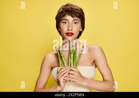 A young woman holding a bunch of asparagus in front of her face. Stock Photo