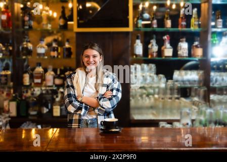 Waitress standing in bar and wiping and polishing beer glass. Bartender woman working in bar counter, preparing and cleaning, work before guests come, Stock Photo