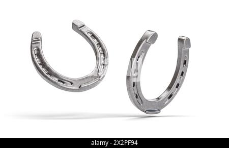 Two shiny metal horseshoes facing each other isolated on a white backdrop Stock Photo