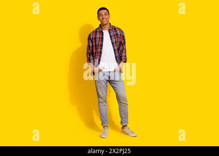 Full length photo of handsome stylish guy wear checkered shirt denim pants keep hands in pockets isolated on vivid color background Stock Photo