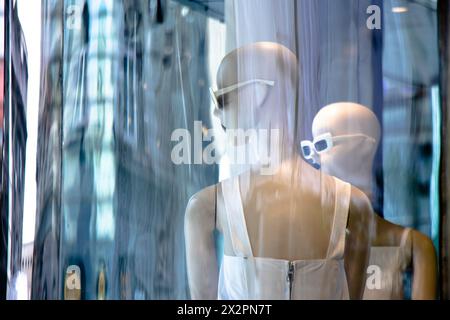 Belgrade, Serbia - April 3, 2024: Blurry Mannequin fashion dolls in white dress with city reflections in the shop window of Max Mara store Stock Photo