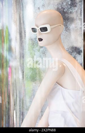 Belgrade, Serbia - April 3, 2024: One bald mannequin doll in white dress with reflections in the shop window of Max Mara store Stock Photo