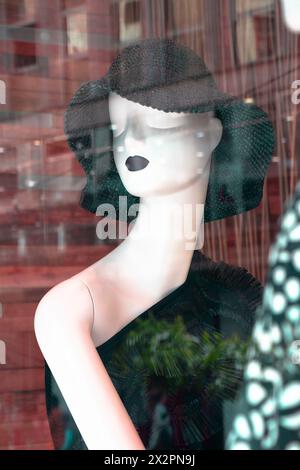 Belgrade, Serbia - April 3, 2024: Mannequin fashion doll wearing black crochet sun hat with reflections in the shop window of Max Mara store Stock Photo