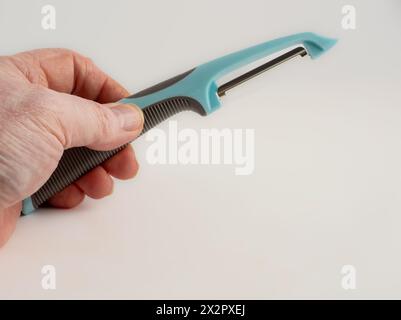 chef holding a blue potato vegetable peeler isolated on a white background Stock Photo