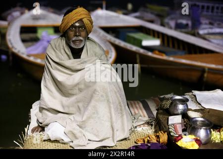 Hindu priest on a platform next to the Ganges River in the predawn at Varanasi, India Stock Photo