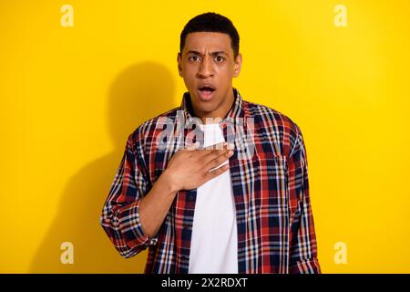 Photo of shocked confused worried nervous man hand chest open mouth unexpected unbelievable news isolated on yellow color background Stock Photo