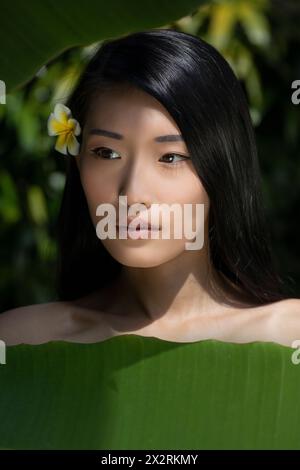 Beautiful young woman near banana leaves Stock Photo
