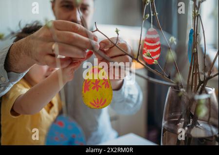 Father and son decorating painted Easter eggs on twigs Stock Photo
