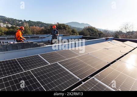 Engineers installing solar panels on rooftop Stock Photo
