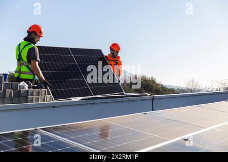 Two engineers installing solar panel on rooftop Stock Photo