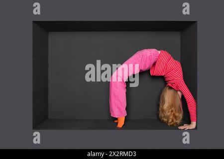 Blond teenage girl bending backward against black backward Stock Photo