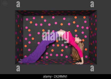Teenage girl bending backward over black background with colored dots Stock Photo