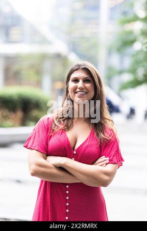 Smiling young woman standing with arms crossed Stock Photo