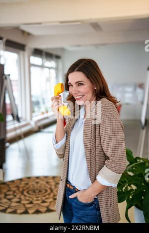 Smiling businesswoman talking on telephone in office Stock Photo