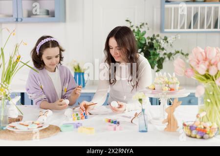 Mother and daughter painting eggs for Easter at home Stock Photo