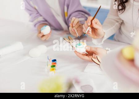 Woman decorating Easter eggs with daughter at home Stock Photo