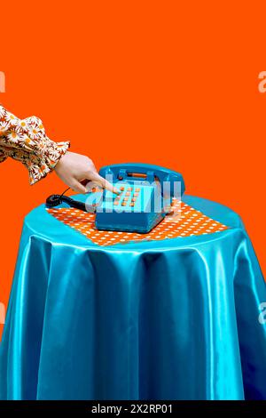 Hand of woman dialing on keypad of telephone against orange background Stock Photo