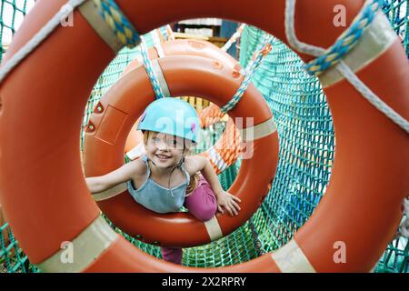 Smiling girl doing obstacle course at rope park Stock Photo