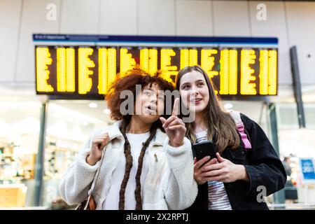Woman gesturing with friend standing at railroad station Stock Photo