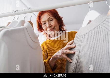 Senior woman with tops hanging on rack in closet Stock Photo