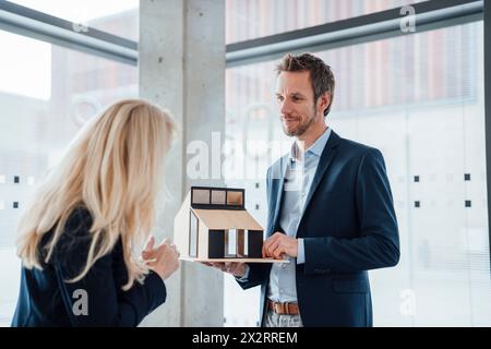 Smiling architects discussing over model house with colleague in office Stock Photo