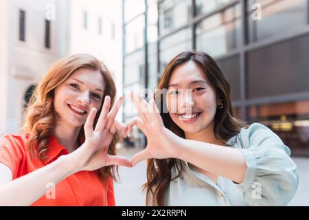 Happy friends making heart shape gesture Stock Photo