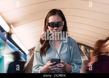 Woman wearing smart glasses and using smart phone at subway station Stock Photo