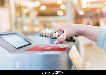 Hand of woman scanning QR code through smart phone at turnstile Stock Photo